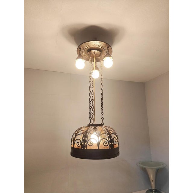 This decorative pendant lamp in the Art Nouveau/Art Deco style stands out with its artfully hand-forged metal frame and...