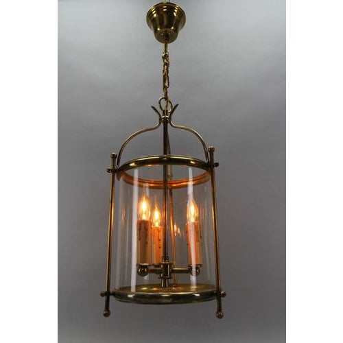French brass and clear glass three-light round hanging lantern from circa the 1950s. This adorable three-light pendant...