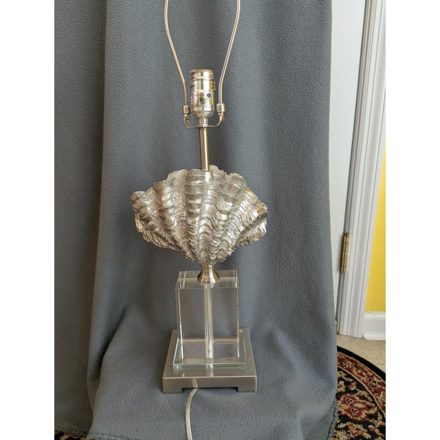 Giant silver tone clamshell sits atop a lucite base. The clam shell measures approximately 9" X 4" atop the 6" X 5" base.