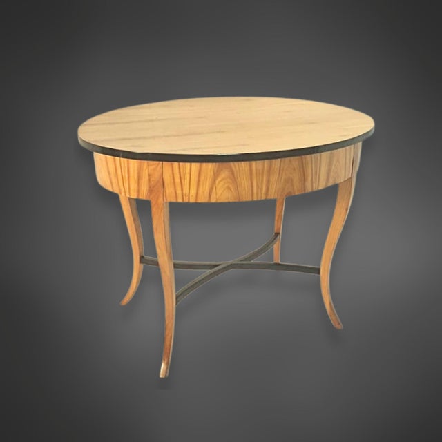 Oval side table from the Biedermeier period, circa 1825. The tabletop is cherry veneered and framed by an ebonized border...
