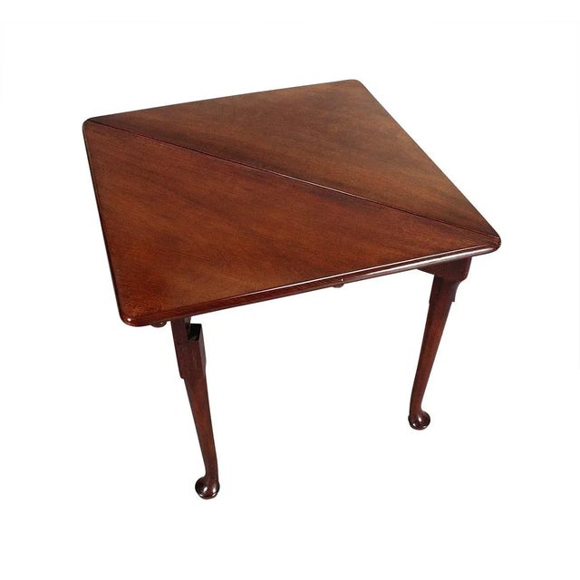 A mahogany handkerchief table. With the leaf down, the table is triangular. When the leaf is raised and supported by the...