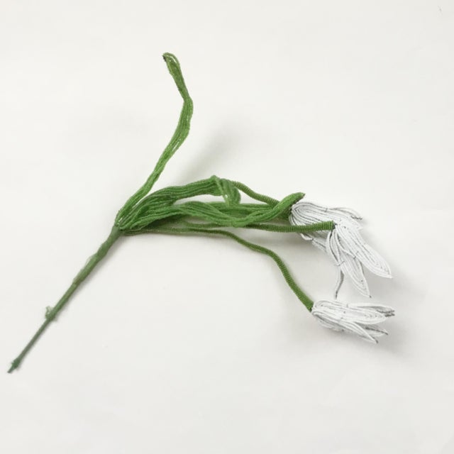 This is a handmade floral arrangement made of white and translucent green seed beads, wire and thread.