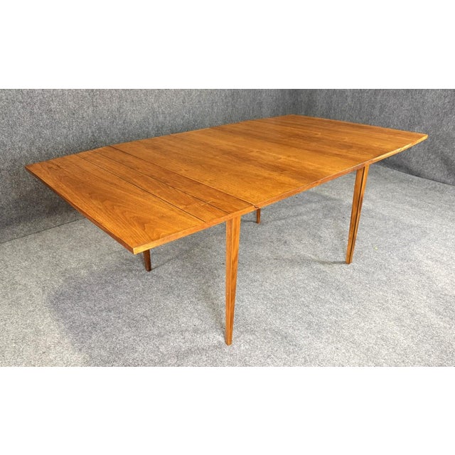 This mid-century modern Lane Tuxedo drop-leaf dining table showcases warm walnut tones accented by the signature bowtie...