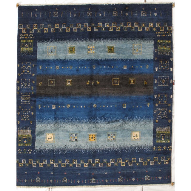 Vintage hand-knotted Persian Lori Gabbeh rug featuring a deep blue field with horizontal bands and intricate tribal motifs...