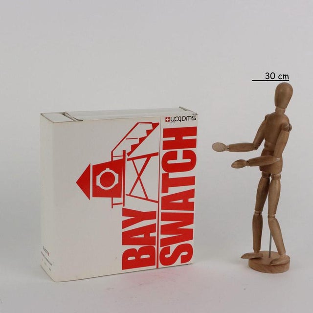 Bay Swatch box containing watch and gadgets. This piece is attributed to the mentioned designer/maker. It has no...