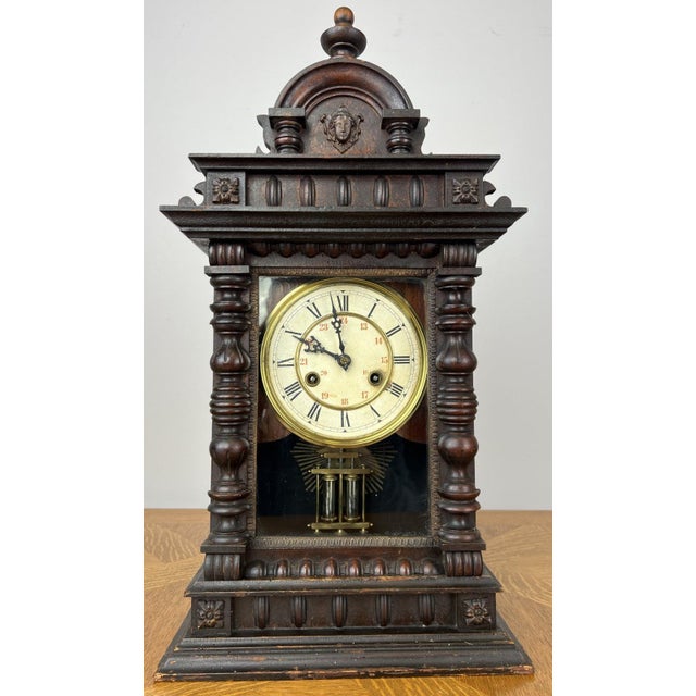 A beautifully styled vintage Junghans wooden clock featuring an elegant architectural case with turned columns, decorative...