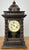 A beautifully styled vintage Junghans wooden clock featuring an elegant architectural case with turned columns, decorative...