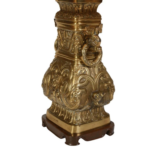 A large bronze Asian lamp with two handles with rings and ornate decoration. Sits on a wood base. Lamp recently rewired.