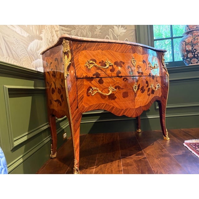 A beautifully inlaid Louis XV ormolu-mounted commode in kingwood and tulipwood marquetry with a molded breccia marble top....