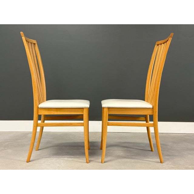 A set of four mid century modern style solid beech dining chairs with off white seats. Made in Italy. Great overall...