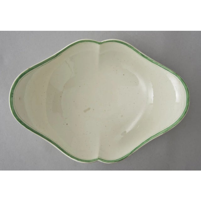 Wedgwood footed compote in an oval shape outlined with a green stripe inside and outside, the outside decorated with a...