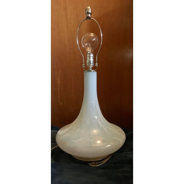 A fresh take on the glass table lamp melding two classic features by combining a mod mid century shape with a clean white...