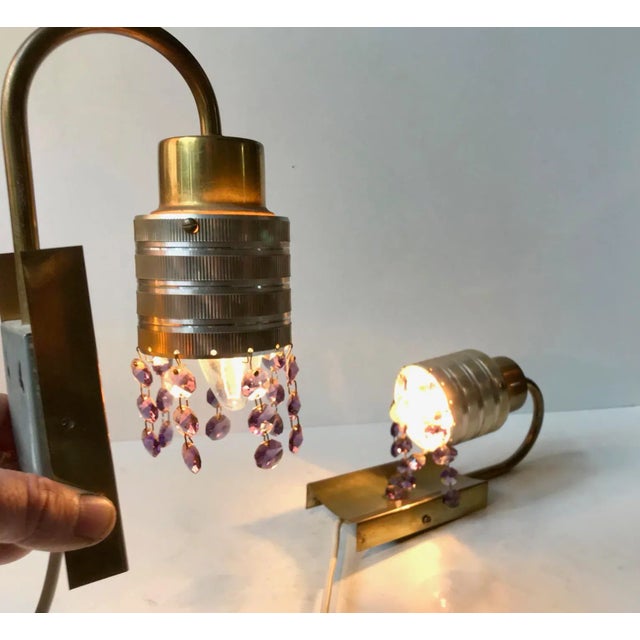 - A pair of mid-century 'Swag' wall lamps - Brass mounts and aluminium engine turned shades - Set with rows of purple and...