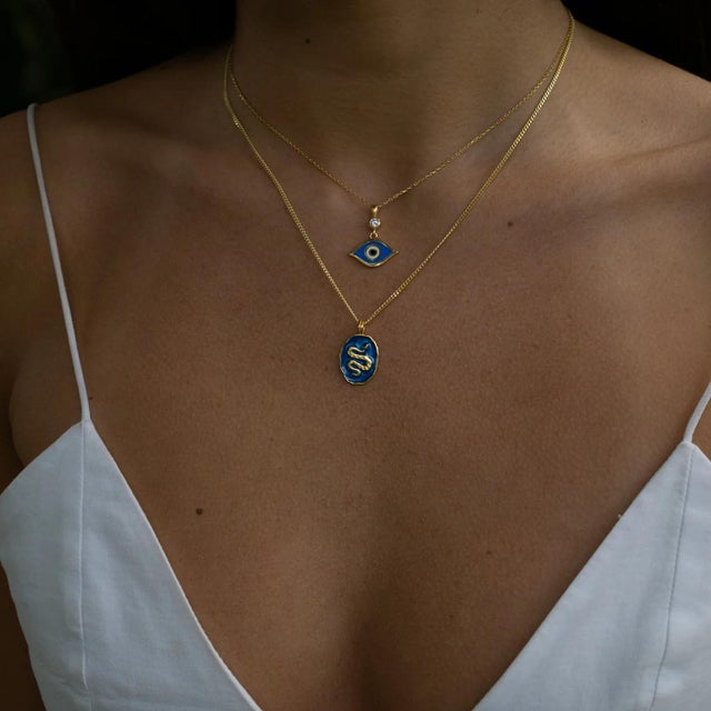 The Guardian Snake Blue Enamel Gold Necklace is a striking piece that blends mystical symbolism with modern elegance. At...