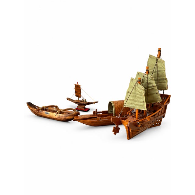 A distinctive collection of four wooden boat models, each with its own character. The group includes a three-masted vessel...