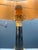 Empire-style table lamp featuring a black marble column base and finely chiseled gilded bronze details. The upper part of...