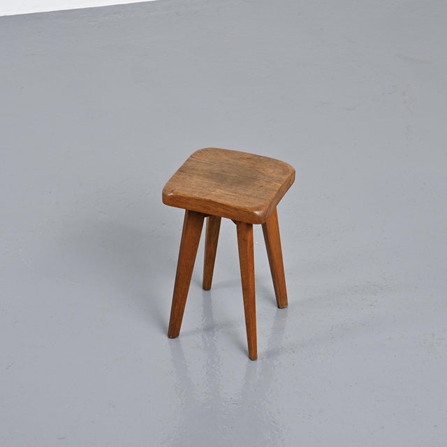 Stool made of solid oak in France in the 1950s. Its square seat with gently softened corners rests on four tapered,...