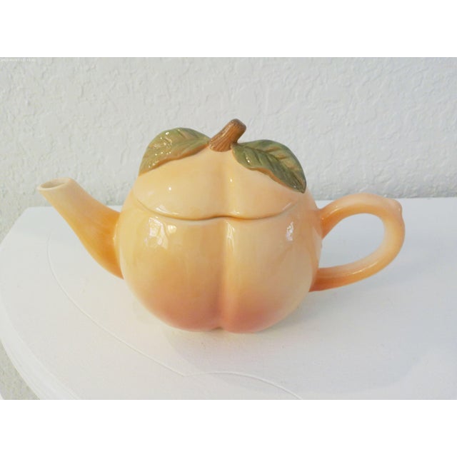 Charming pair of nicely matched ceramic figural peach handled teapots. Larger pot, (11"L x 6"W x 6.5"H), holds 32 ounces,...