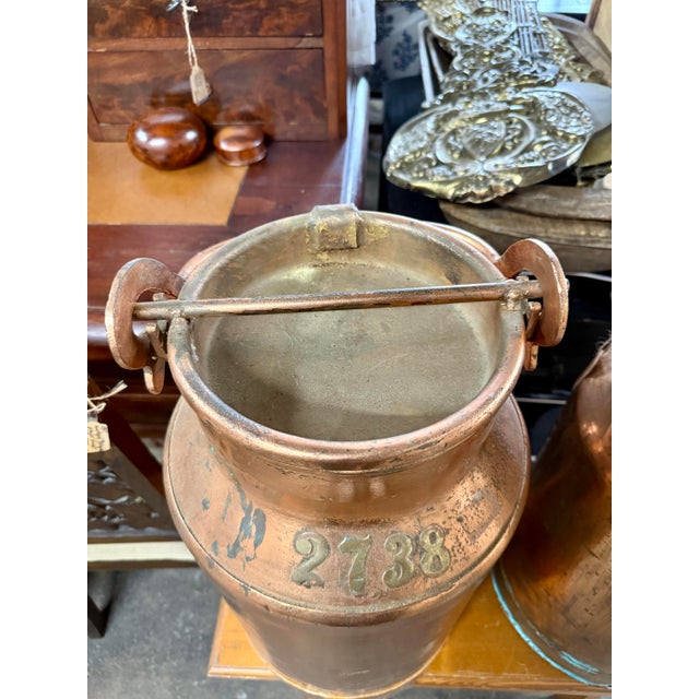 A beautifully aged antique French copper milk can, featuring its original fitted lid, riveted side handles, and rich...