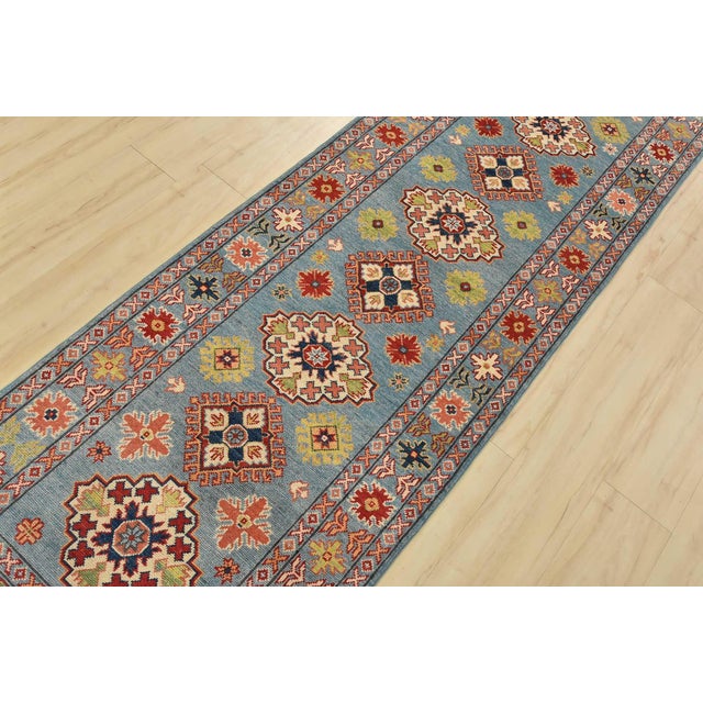 A tribal Caucasian Kazak runner hand-knotted with fine wool on a cotton foundation. This rug features a row of geometric...
