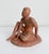 1950s sculpture of a seated male figure, handmade with red clay. Artist signed