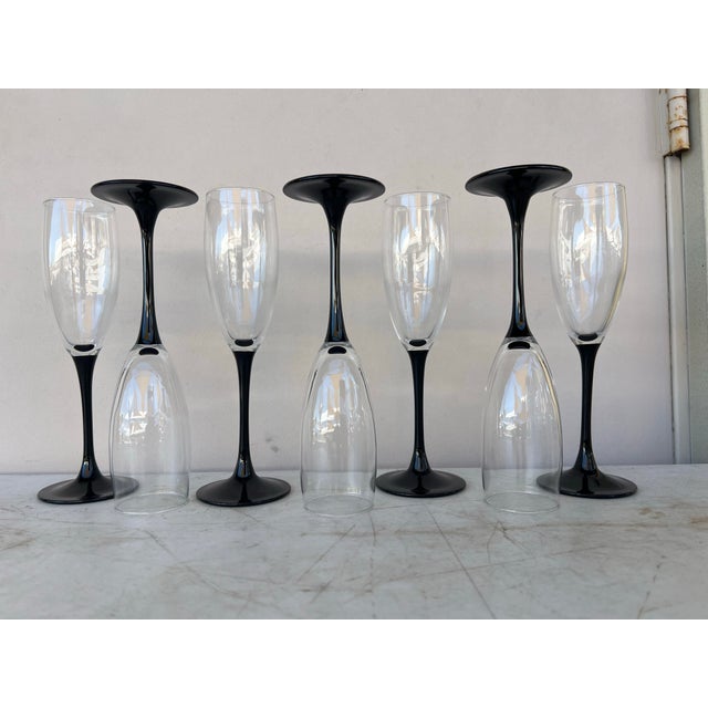 Long stem Flute Champagne Glasses. The bowl is clear glass and the stem/ base is black. The base is 2.75” .The rim is 2”...