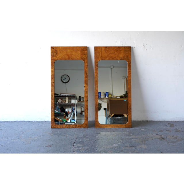 Stunning pair of Mid-Century Modern wall mirrors featuring bookmatched burl wood frames with a warm, honey-toned grain and...