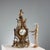 Bronze mantel clock in the shape of a lyre surmounted by a figure of Cupid wearing a plumed helmet. Note the rich and...