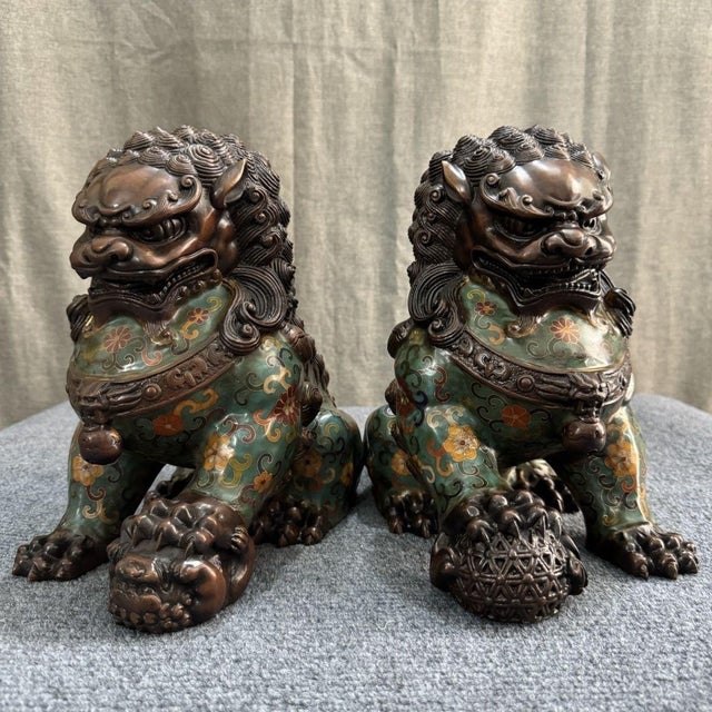A striking pair of large Chinese Cloisonné enamel Buddhist lions (foo dogs). Each figure is seated on its haunches, with...