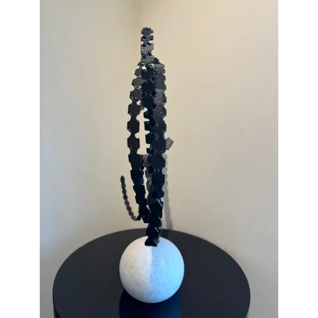 Elongated, flowing thistle leaves made of iron branch out of a solid, rounded white marble base.