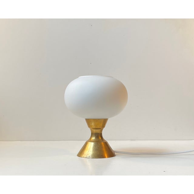 A small, simple yet elegant Table Lamp executed in brass and featuring a white frosted glass shade in mushroom shape. It...