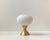 A small, simple yet elegant Table Lamp executed in brass and featuring a white frosted glass shade in mushroom shape. It...