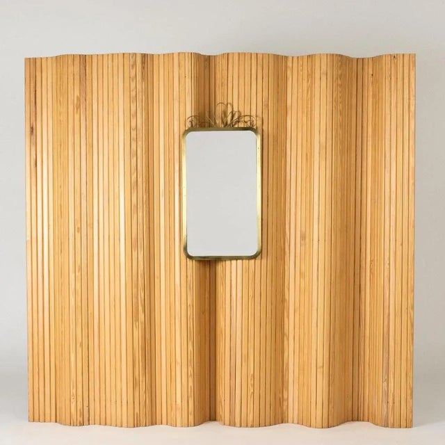 Elegant wall mirror from Ystad Metall, with a rounded corners brass frame. Decorative bow on top. This piece has an...