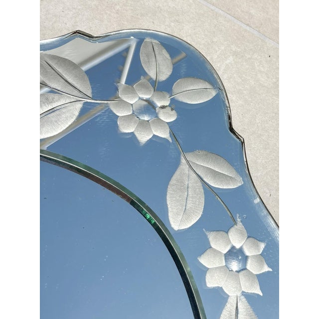 An elegant antique glass mirror featuring a refined silhouette and finely acid-etched floral ornamentation on its frame....