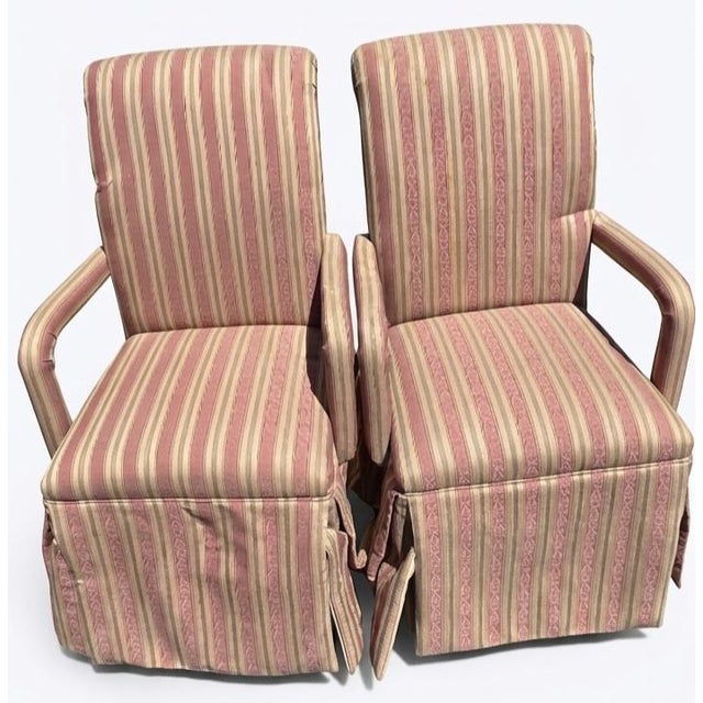 These matching pair of vintage-style, upholstered skirted armchairs featuring a classic, formal silhouette.