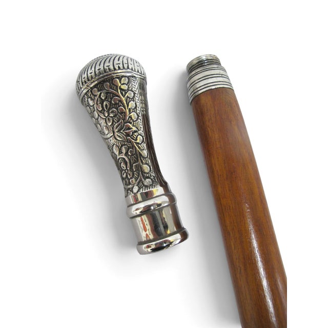 Victorian era walking stick cane. Wood shaft with floral chased silver-plated handle. Handle unscrews to reveal an open...