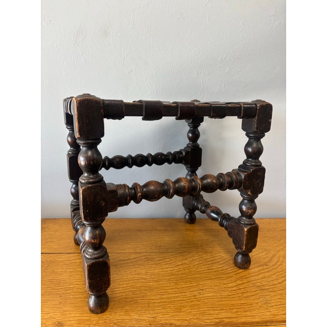 This early 20th century English low stool is a quiet masterpiece of utility and craftsmanship. Its oak base, elegantly...