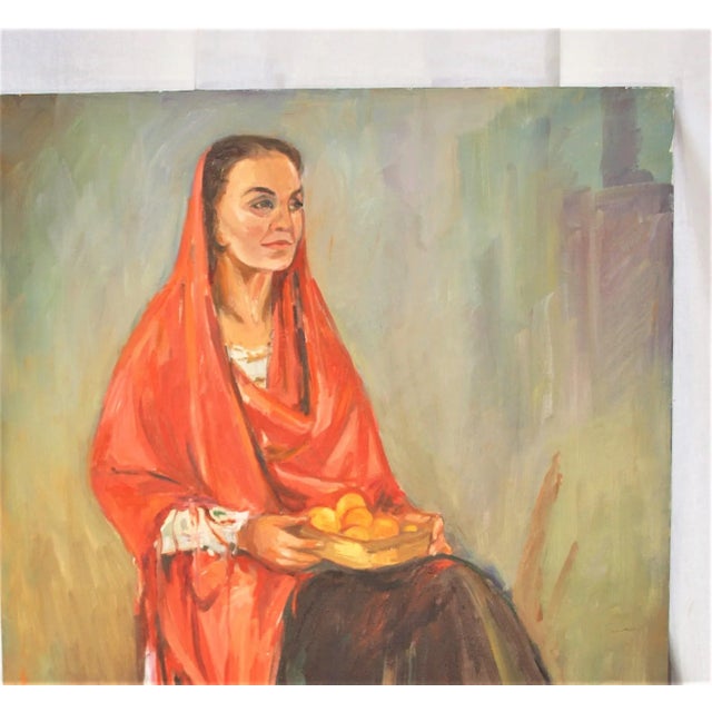 A vintage. decorative unframed oil painting of an old woman sitting on a chair. She appears Hispanic and is holding a...