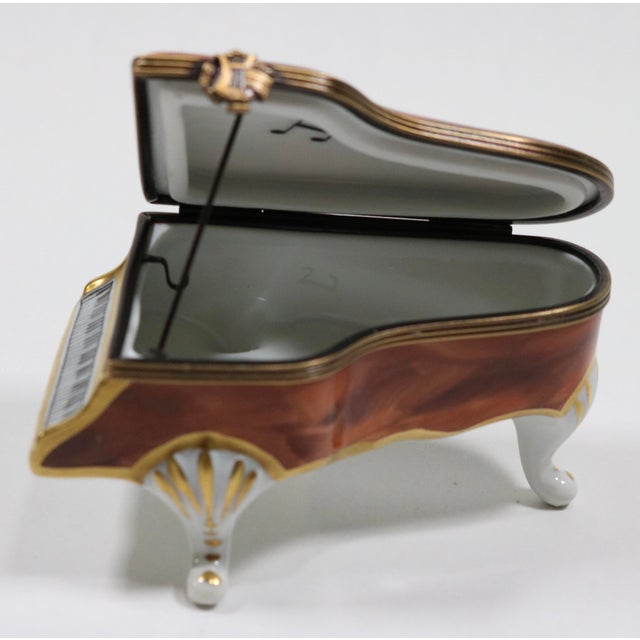 Beautiful Limoges trinket box with a wood grain painted finish. It includes the pole to keep the lid up on the piano. I...