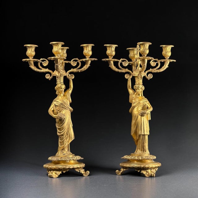 An exceptional pair of French Empire Revival gilt bronze figural candelabra, masterfully sculpted as elegant classical...