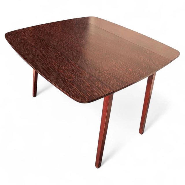 This vintage drop-leaf table offers a timeless mid-century dining solution that combines style, function, and space...