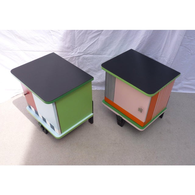 Pair of small, colorful bedside tables on three legs with one door. Lacquered/varnished wood frame Multicolored with...