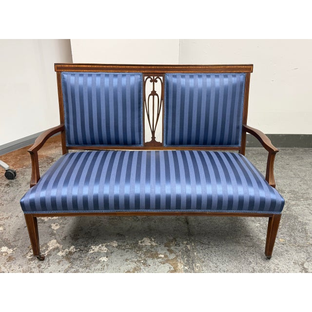 Design Plus Gallery presents an Antique Edwardian Settee. A mahogany settee with decorative banded inlay, a pierced...