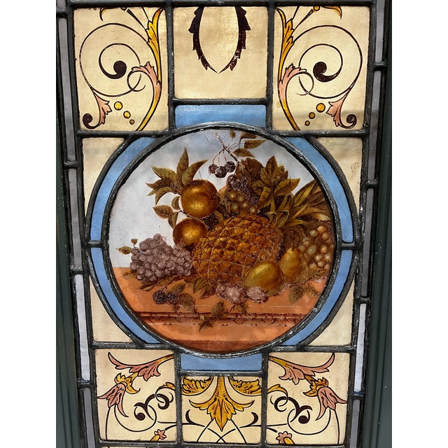 A leaded stained glass window panel with a hand-painted fruit motif, likely in the Victorian or Arts and Crafts style,...