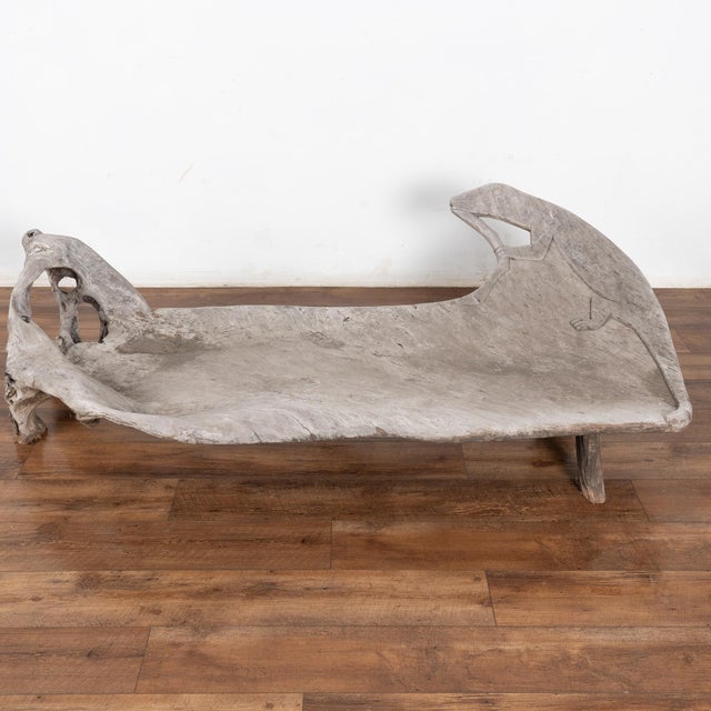 Worn and weathered through the elements, the seat of this teak root bench is one solid piece of wood, with a carved Iguana...