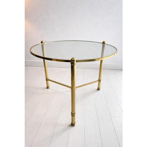 Elegant round cocktail table featuring a refined brass structure and glass top, designed in the style of the renowned...