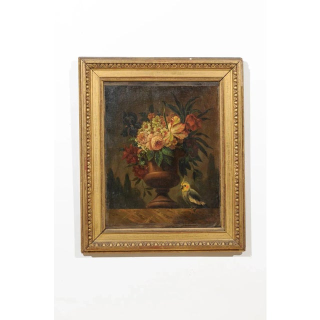 A French framed oil on canvas still-life painting from the 18th century, depicting a bouquet of flowers and a parakeet....