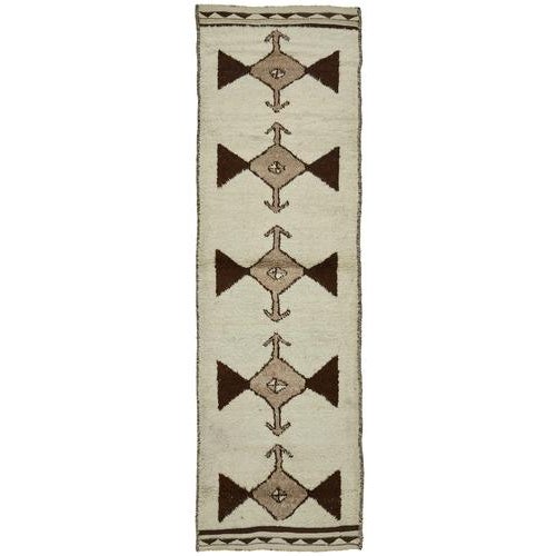 This exquisite runner rug is a rare example of tribal craftsmanship, hand-knotted by the women of the Herki tribe during...