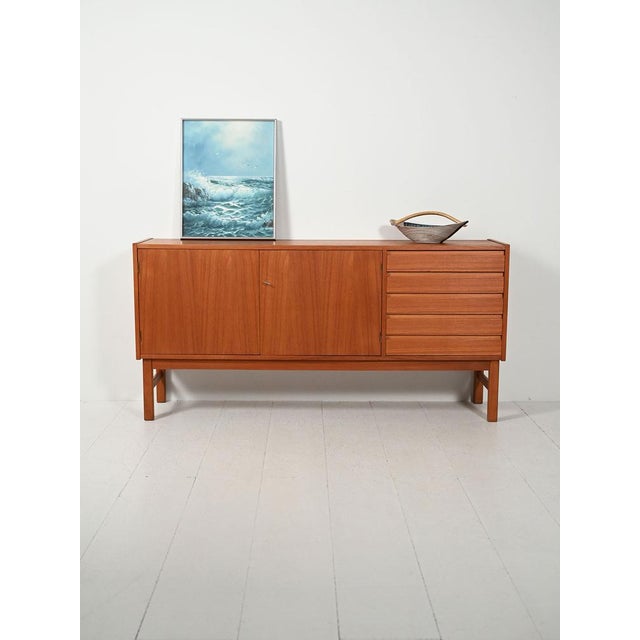 Scandinavian teak sideboard from the 1960s with two doors and drawers on the right, recessed handles, and square legs....