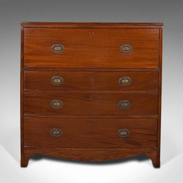 This is an antique secretaire cabinet. An English, mahogany chest of drawers with drop front writing desk, dating to the...